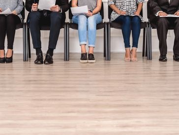 People seated, holding papers, ready for an interview.