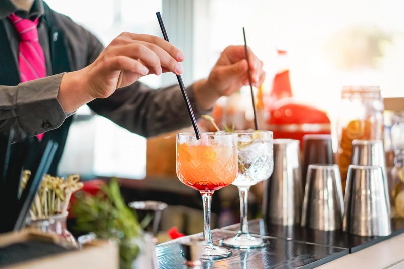 Young bartender making cocktails at bar counter - Barman serving drinks - Work, passion and mixologist concept