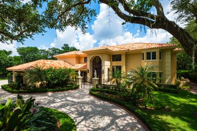 Luxurious Mediterranean-style house with tiled roof and lush greenery.
