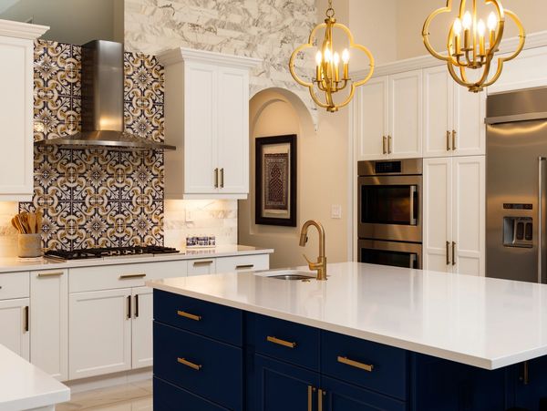 Luxury modern kitchen with navy island, gold accents, marble flooring, and custom tile backsplash