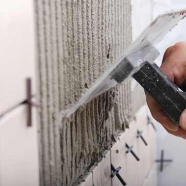 Applying mortar to a wall for tiling.