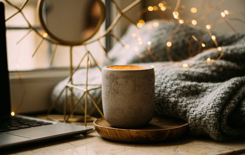 Cozy work place at home for freelancer, with laptop, knitted blanket and burning candle