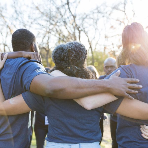 Group hug outdoors with sunlit background.