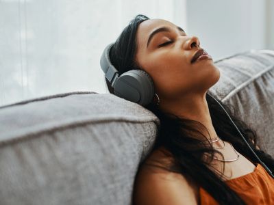 Young woman relaxing with headphones on a couch.