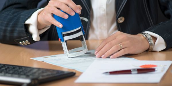 Person stamping a document in an office setting.