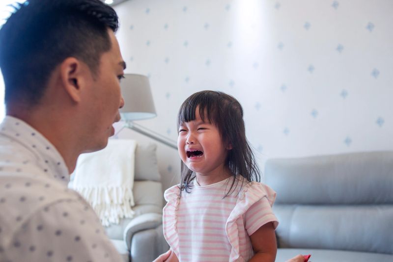 Close up of Asian father consoling cure crying daughter in living room of the house. concept of parenthood