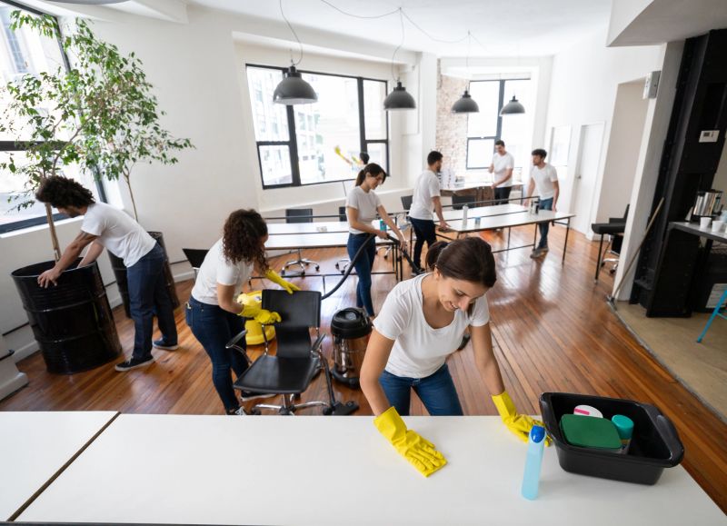 Latin american cheerful cleaning contractors at an office leaving it spotless