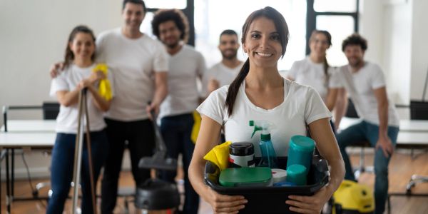 Grupo de personas sonriendo con productos de limpieza.