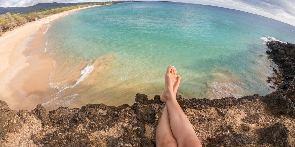 Person relaxing with feet up overlooking a beautiful beach and ocean.
