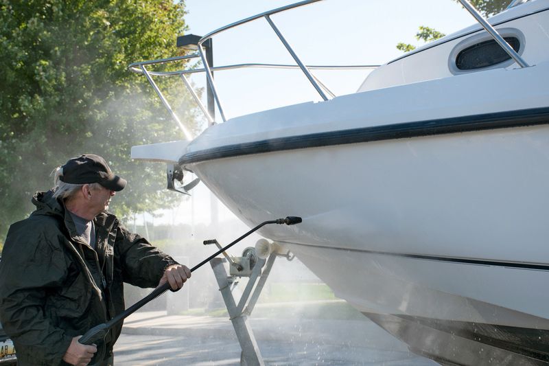 Caucasian man using pressure washer to clean boat hull