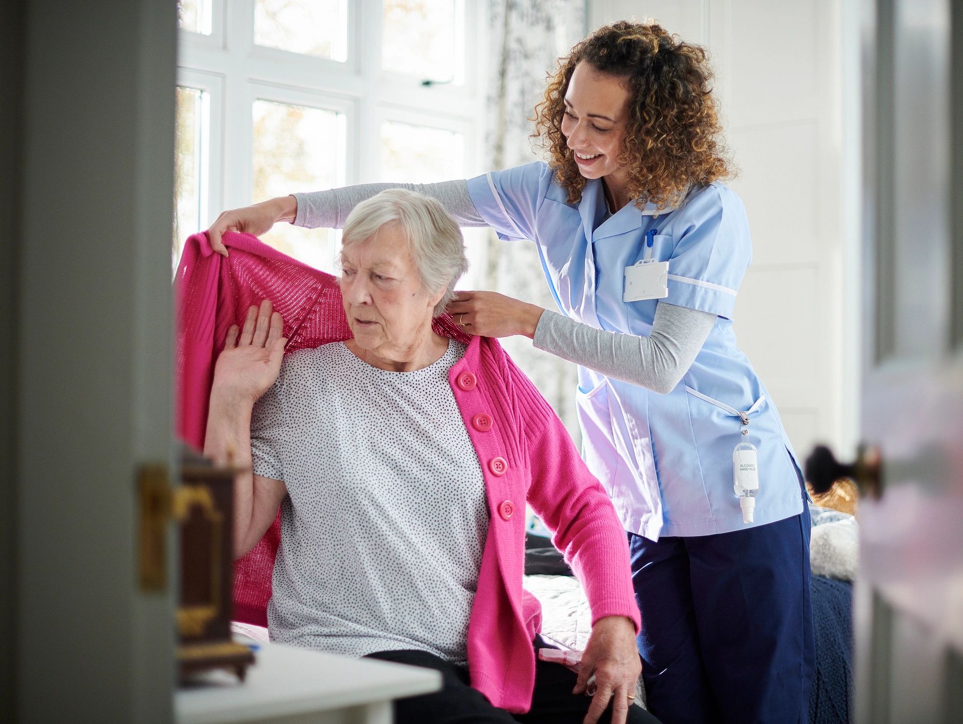 Nurse helping elderly woman with a pink cardigan.