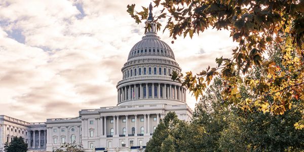 The U.S. Capitol building with cloudy sky and fall foliage.