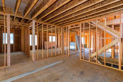 Interior view of a house under construction with exposed wooden framing.