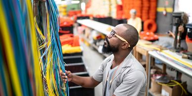 Man inspecting colorful cables in a workshop.
