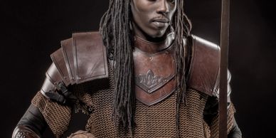 A man in medieval armor holding a sword, ready for battle.