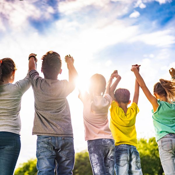 Children holding hands with the sun shining.