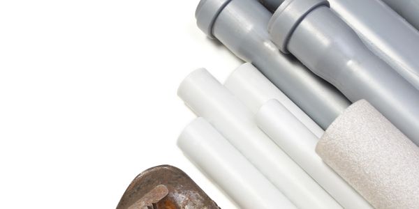 Plumbing tools and pipes arranged on a white background.