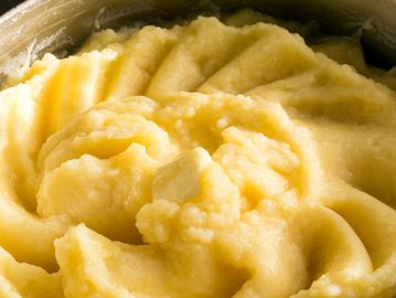 Close-up of creamy mashed potatoes with a melting butter pat.