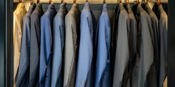 Row of blue and gray suits hanging on hangers.