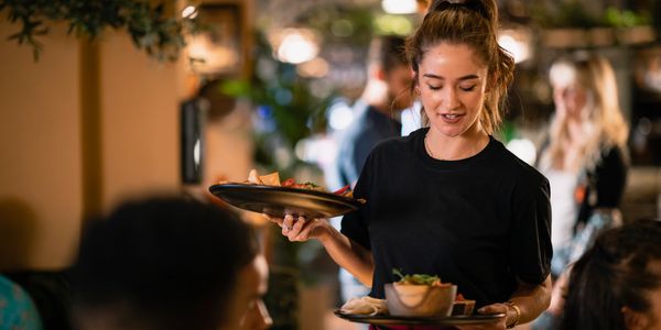 Waitress serving food to customers in a cozy restaurant.