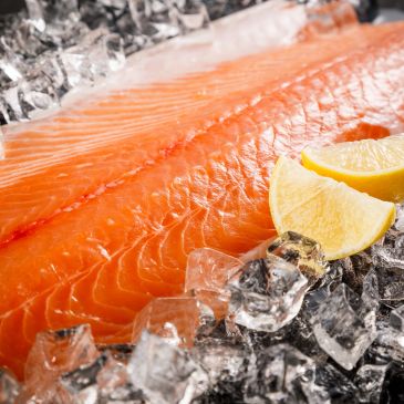 Fresh salmon fillet on ice with lemon slices.