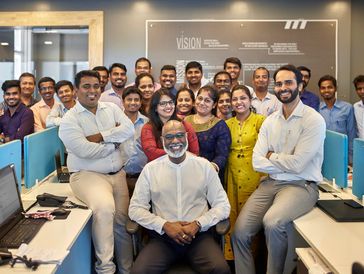 A diverse group of office colleagues posing happily in a modern workspace.