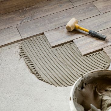 Floor tiles being installed with adhesive and mallet.