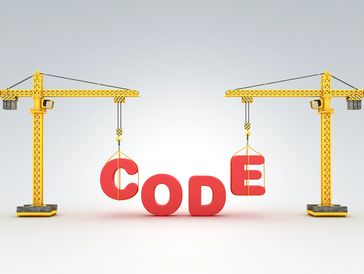 Construction cranes lifting letters spelling 'CODE'.