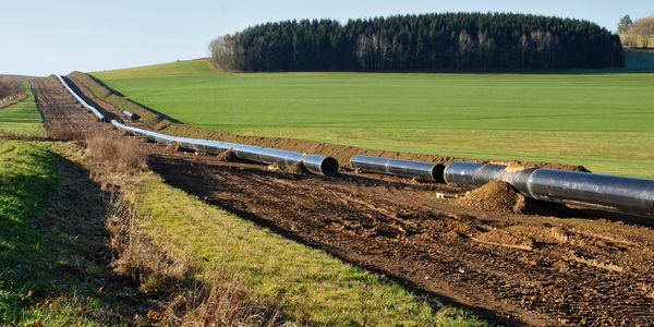 A pipeline under construction across a green field.