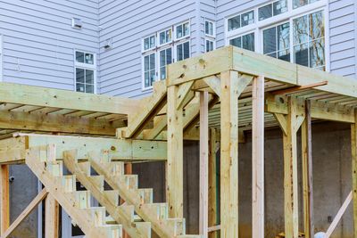 Wooden deck under construction attached to a house with stairs.