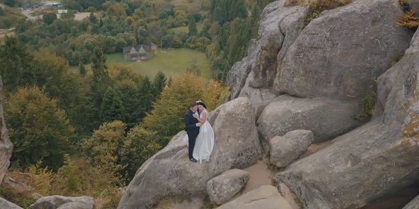 Ariel and drone image of a bride and groom on and rock cropping on the side of a mountain