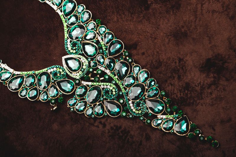 Luxury necklace with green gemstones on the brown velvet background