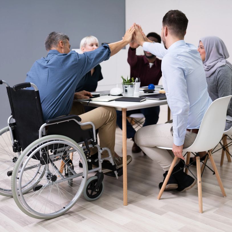 Diverse group high-fiving in a meeting.