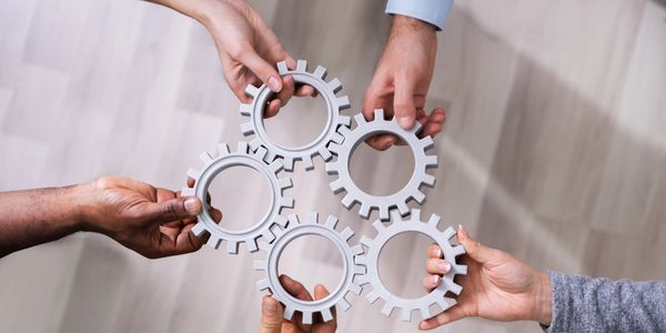Five hands holding interconnected gears symbolizing teamwork.