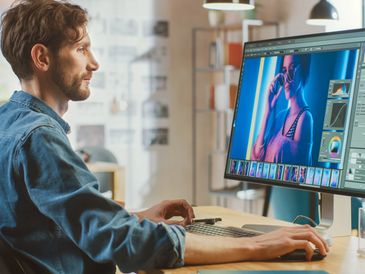 A man editing a vibrant portrait photo on a computer.
