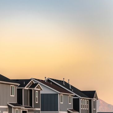 Row of modern suburban houses at sunset with mountains in the background.