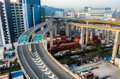 Empty elevated highway near a busy container terminal in an urban area.
