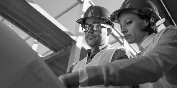 Two construction workers reviewing plans on-site.