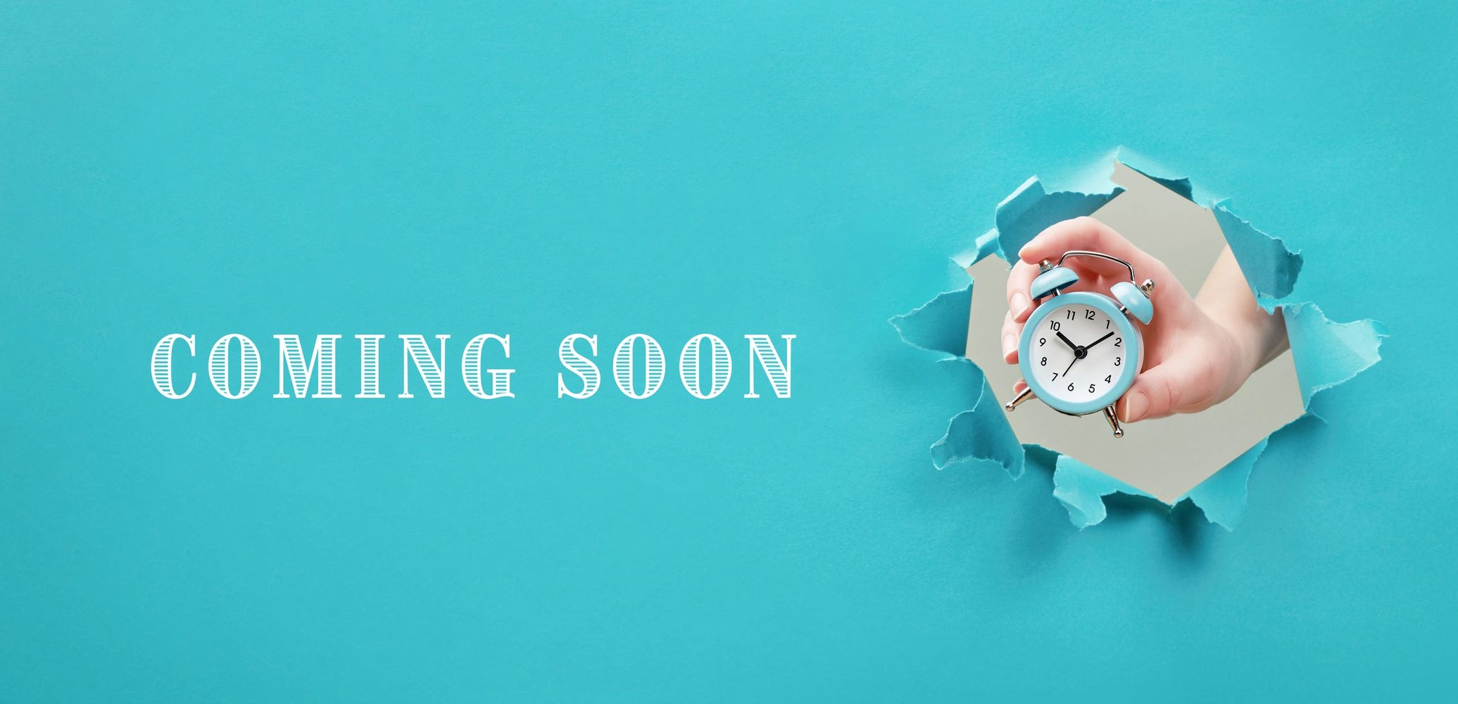 Hand holding blue alarm clock through torn paper with 'Coming Soon' text.