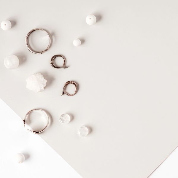 Minimalist arrangement of silver jewelry and white beads on a light background.