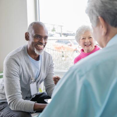 Three seniors engaged in a cheerful group conversation indoors.
