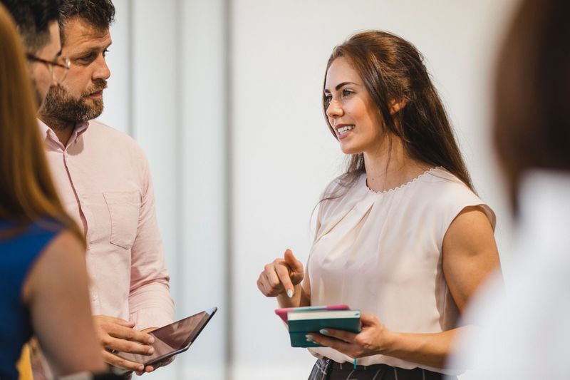 Cheerful young woman explaining to coworkers, support, collaboration, organisation