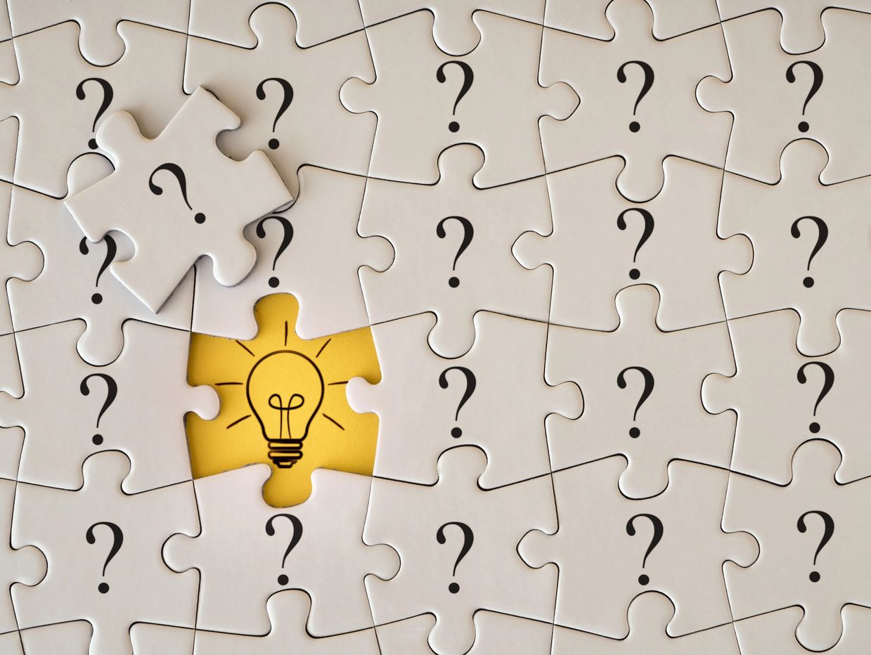 Puzzle pieces with question marks revealing a bright lightbulb idea.