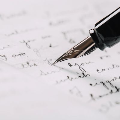Close-up of a fountain pen writing on paper with cursive handwriting.