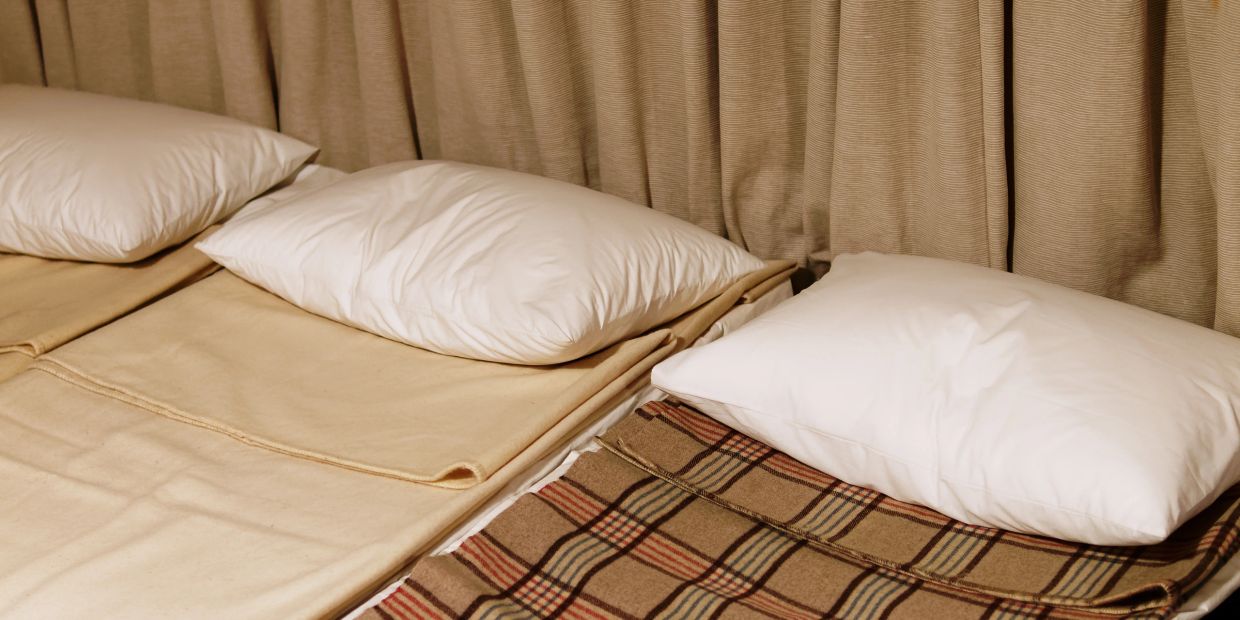 Two beds with pillows and blankets in a cozy room.
