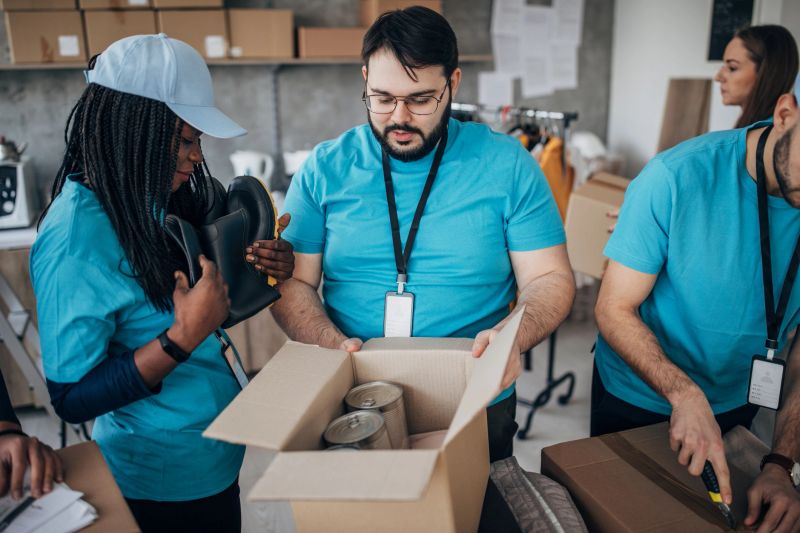 Multi-ethnic group of people, diverse volunteers packing donation boxes in charity food bank.