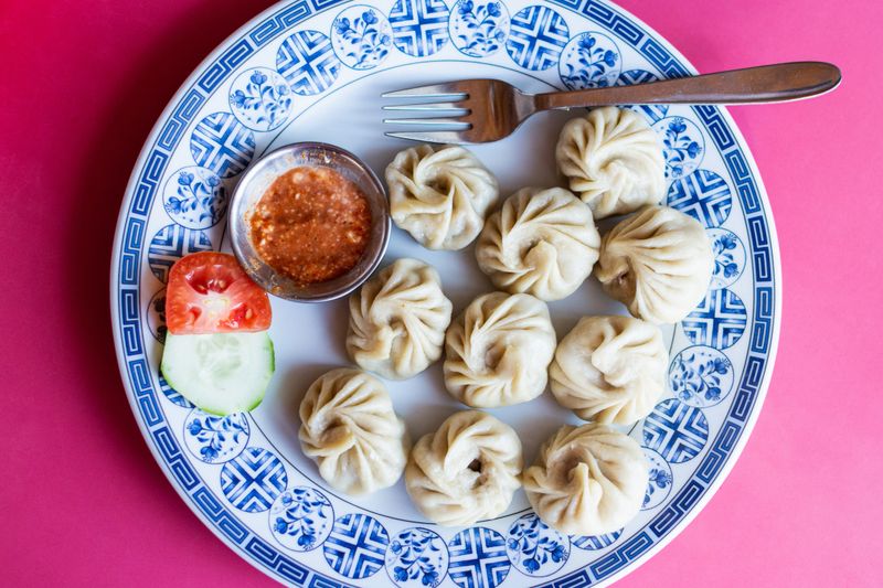 Flat lay still life of Nepalese momo dumplings with yak meat served on a plate with dipping sauce