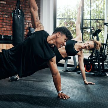 Personas haciendo ejercicio en pareja en un gimnasio.