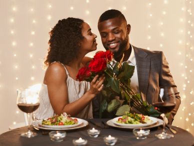 Couple sharing a romantic moment with roses at dinner.