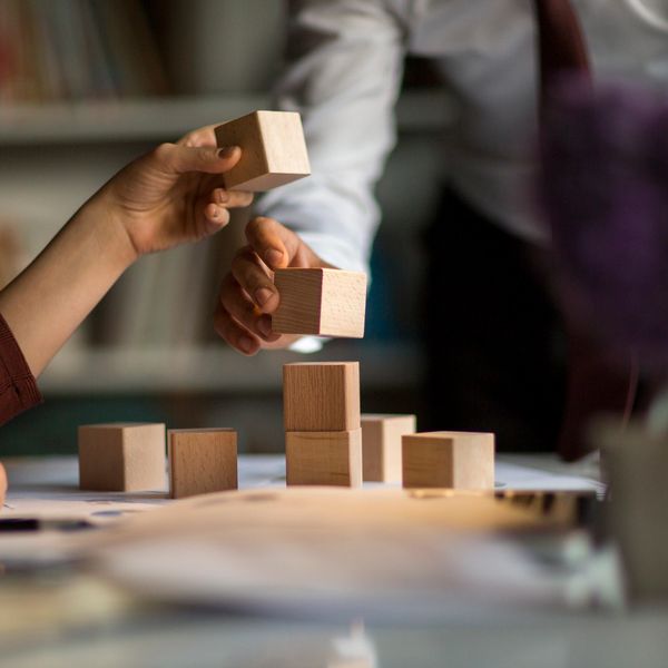 Two people stacking building blocks together.